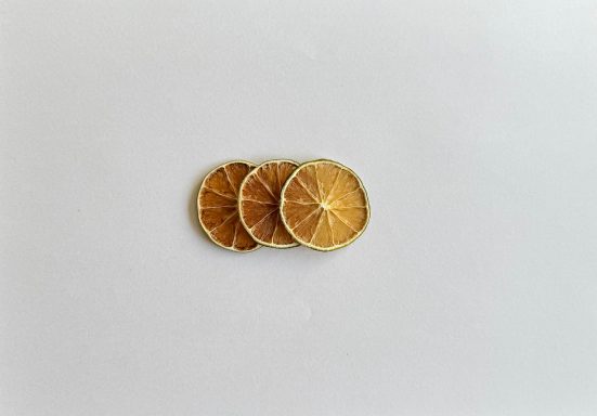 Tre torkade citronskivor liggande på en ljus bakgrund.